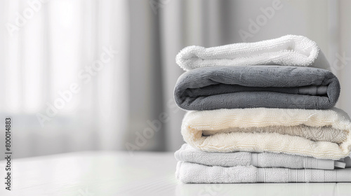 Stack of folded towels on plain background with copy-space for text. A lot of stacked towels in white and grey color tones were displayed on a white curtain background.