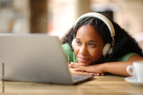 Black woman with headphone watching media content on laptop