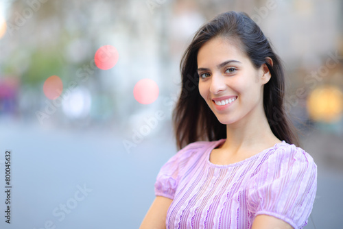 Happy woman with perfect smile in the street looks at camera