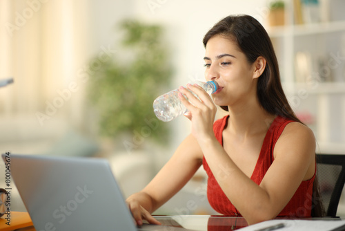 Student drinks water from bottle at home