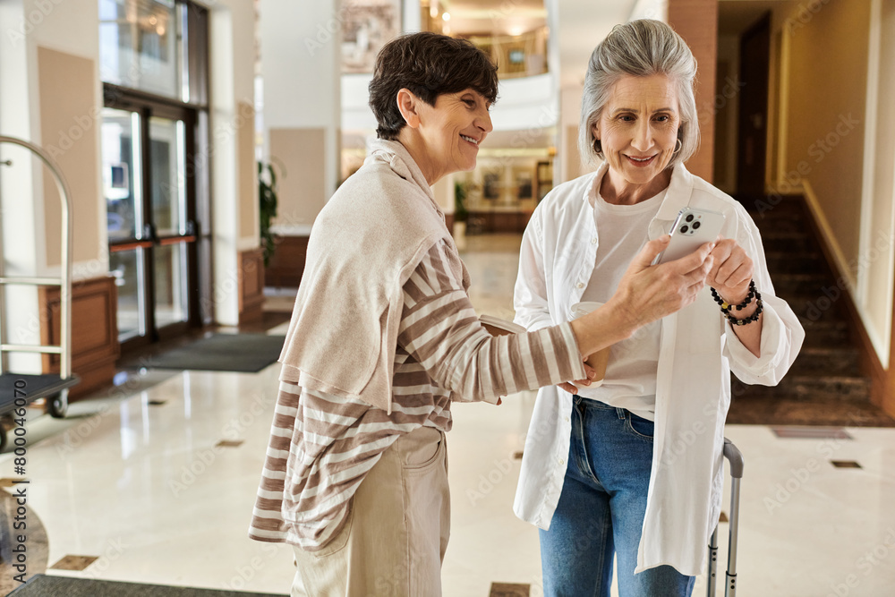 Fototapeta premium Senior lesbian couple share a moment while looking at a cell phone.
