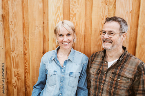 Happy Middle-Aged Couple Laughing Together in Front of Wooden Wall