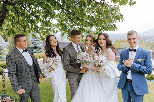 A group of people, including a bride and groom, are posing for a photo in a park