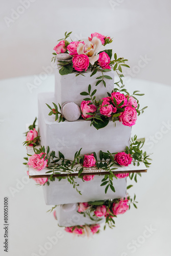 A three tier cake with pink flowers and pink frosting
