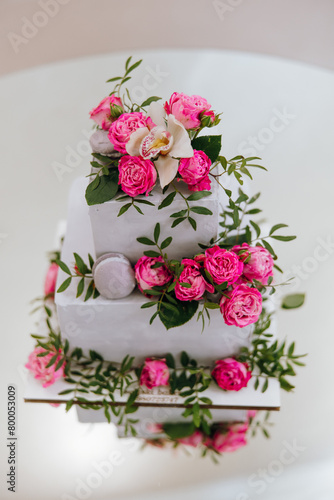 A three tier cake with pink flowers and a white and pink orchid on top