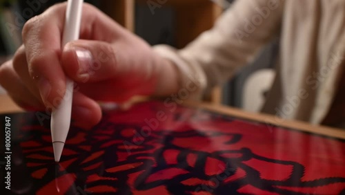 A teenager carefully draws lines on a tablet pad using an electronic pen and zoom and pan gestures with his second hand. photo