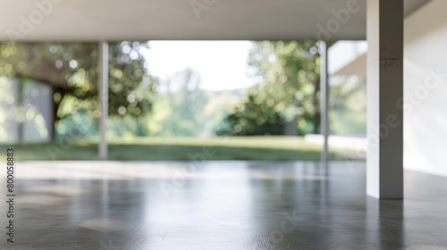 View of a minimalist interior with a blurred green outdoor background through the open architecture.