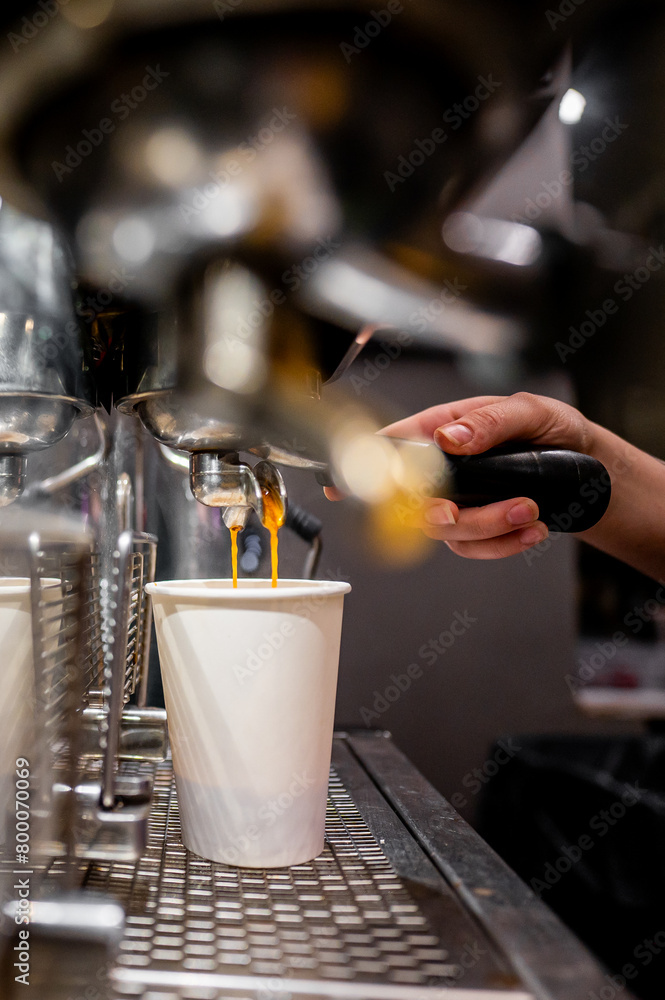 Close-up of a barista’s hand operating an espresso machine, filling a white cup with fresh coffee, capturing the artistry of coffee making Close-up of a barista’s hand operating an espresso machine, filling a white cup with fresh coffee, capturing the artistry of coffee making