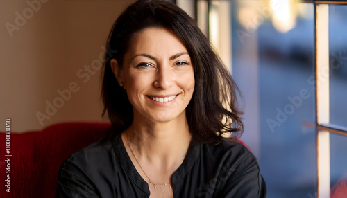 The pleasant-looking middle-aged woman  smiling towards the camera in close-up