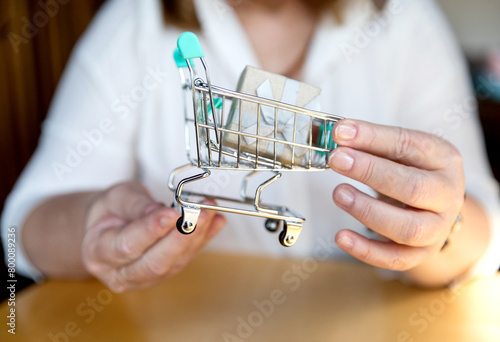 Shopping cart - business woman shopper. Woman showing holding mini shopping cart with the gift. Happy shopping or consumer loan concept with female professional.