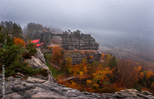 Hrensko, Czech Republic - Panoramic view of the famous Pravcicka Archway (Pravcicka Brana) in Bohemian Switzerland National Park, the biggest natural arch in Europe on a foggy day with autumn foliage