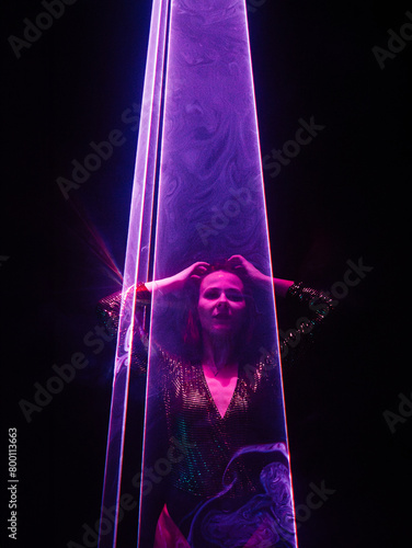 Beautiful woman under violet illumination, laser light, neon party night club. Performance, projection mapping. Interactive exposition installation.