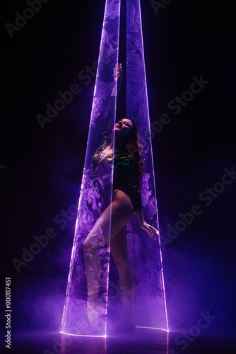 Ballet dancer in pointe under multicolor neon laser light on stage. Woman ballerina posing in dark room. Performance, projection mapping. Interactive installation, Optical visuals concept