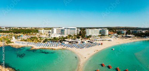 Ayia Napa, Cyprus - 15th april, 2023: aerial fly over Luxury hotel buildings with pools by beach with island greenery panorama.White sand most famous in Cyprus - Nissi beach photo