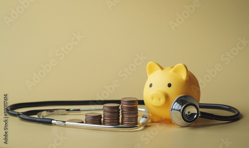 Yellow piggy bank and stethoscope with coin on yellow background. Health and finance concept.
