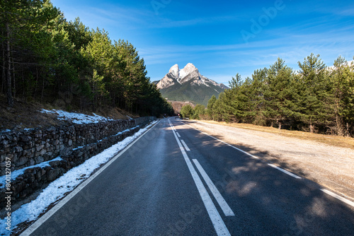 A narrow paved road stretches towards the towering Pedraforca mountain in Catalonia, Spain, inviting travelers to explore photo