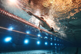 sports advertising underwater photography of a swimmer in a pool swimming freestyle in a sports cap, swimming goggles and dark swimming trunks