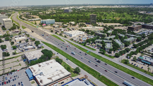 Busy traffic on Stemmons Freeway or Interstate Highway I-35E in Love Field Northwest Dallas, group of office buildings, green urban parks, hotels, restaurants, sunny clear blue sky, aerial view