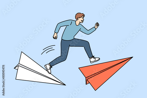 Man leader overcomes dangerous moments in business, runs on large paper airplanes to meet deadline. Ambitious guy wants become leader and be first to overcome path to career success