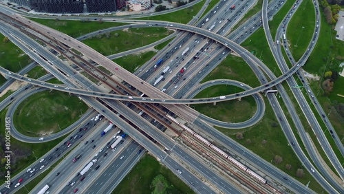 Metropolitan arteries pulsing with cars, aerial showcase of urban pace. Transportation web: Aerial view of a sprawling highway network with seamless vehicular motion. Motorway concept.