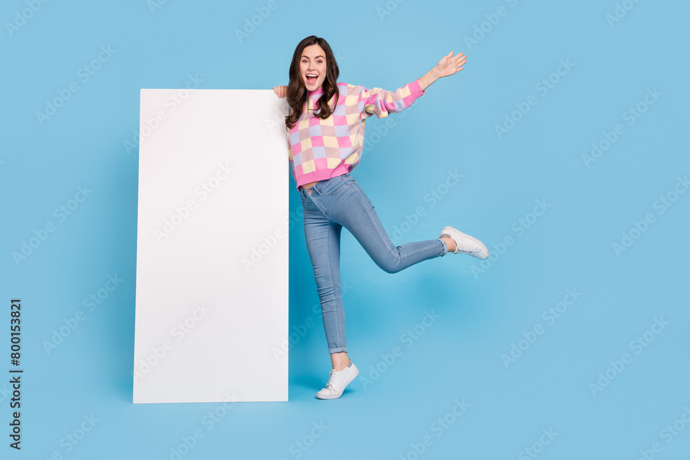Full size photo of young lovely cheerful girl present promo advert isolated over blue color background Full size photo of young lovely cheerful girl present promo advert isolated over blue color background