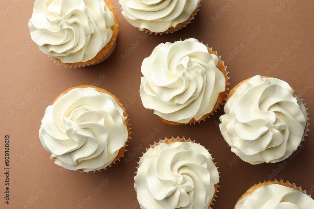 Tasty vanilla cupcakes with cream on dark beige background, top view Tasty vanilla cupcakes with cream on dark beige background, top view