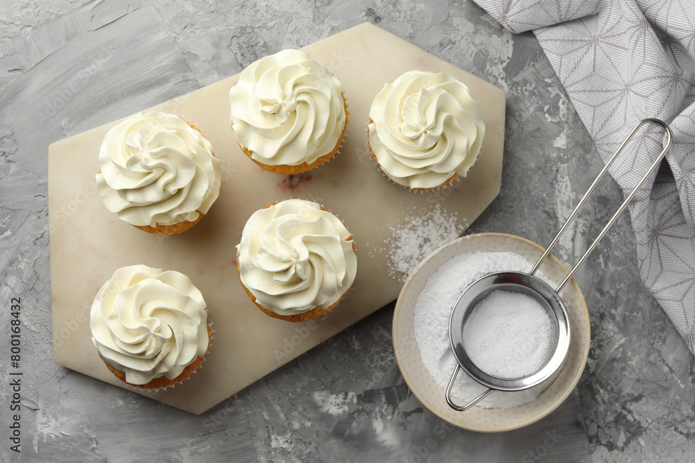 Tasty cupcakes with vanilla cream on grey table, top view