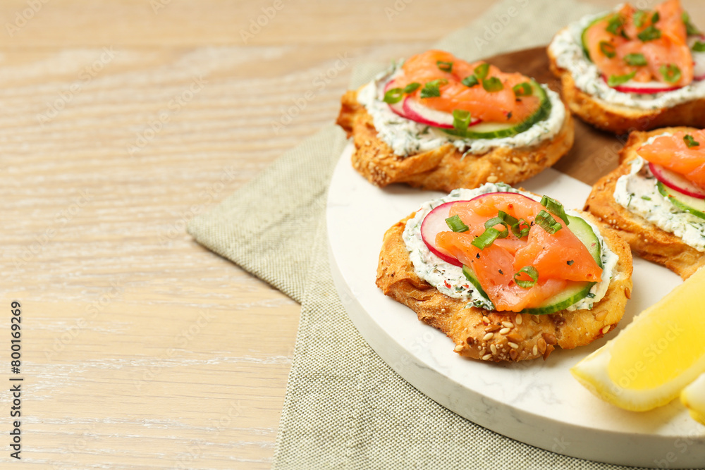 Tasty canapes with salmon, cucumber, radish and cream cheese on wooden table, space for text Tasty canapes with salmon, cucumber, radish and cream cheese on wooden table, space for text