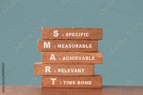 Smart goal for business strategy concept. specific, measurable, achievable, relevant and time-bound text on wooden block with blurred green concrete wall