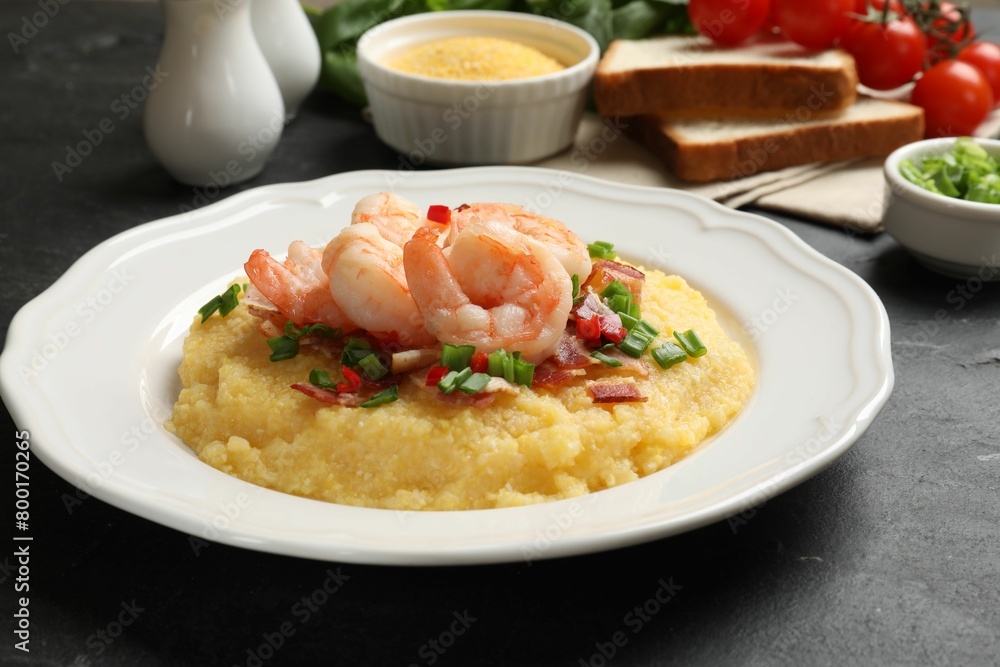 Plate with fresh tasty shrimps, bacon, grits, green onion and pepper on black table, closeup Plate with fresh tasty shrimps, bacon, grits, green onion and pepper on black table, closeup