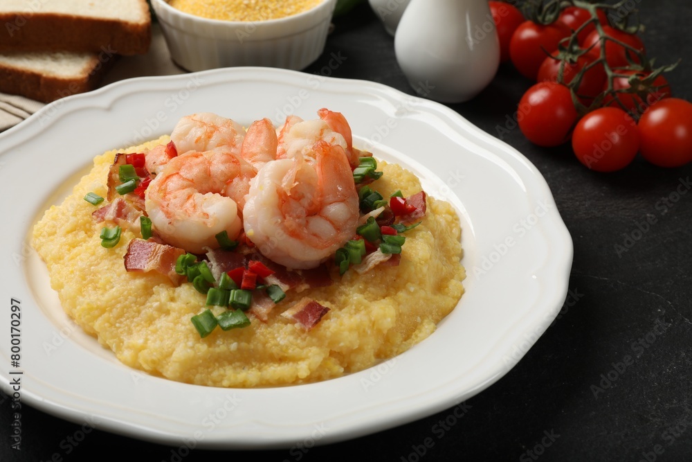 Plate with fresh tasty shrimps, bacon, grits, green onion and pepper on black table, closeup Plate with fresh tasty shrimps, bacon, grits, green onion and pepper on black table, closeup