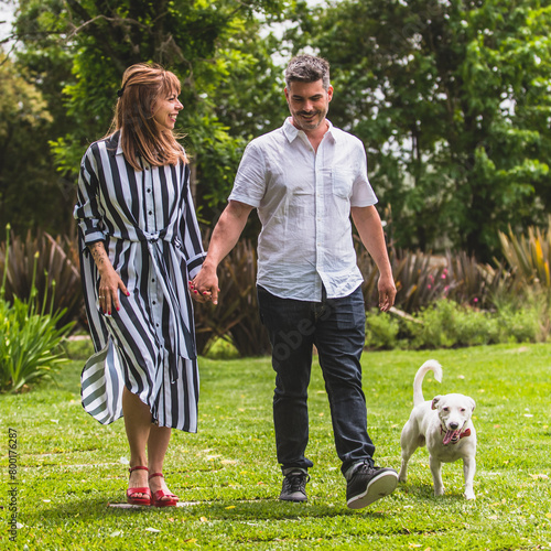 Pareja de novios caminando por el parque, con el perro, familia disfrutando un paseo, Enamorados caminando por el campo, luna de miel. photo