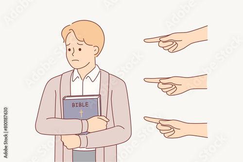 Sad christian man with bible, feeling persecution and oppression, from people pointing fingers