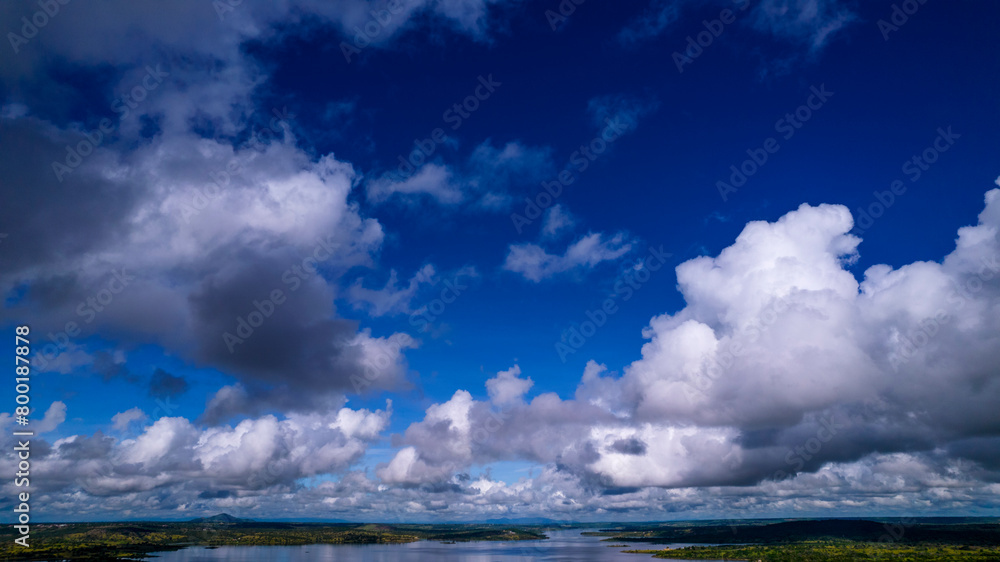 Scattered rain clouds over large lake with green fields
