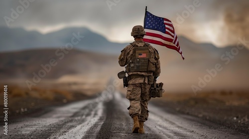 A soldier proudly walks down the asphalt road, holding the American flag as a symbol of his service in the army. The vehicles tires hum on the pavement under the vast sky photo