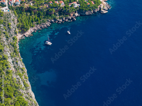 AERIAL: Flying above two sailboats anchored by the rugged coastline of Hvar.