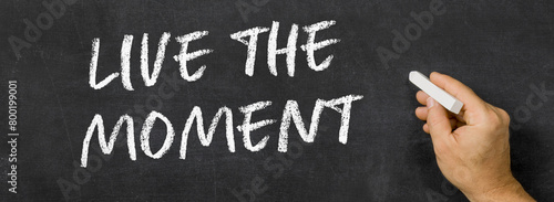  Text written on a blackboard -  Live the moment © Zerbor