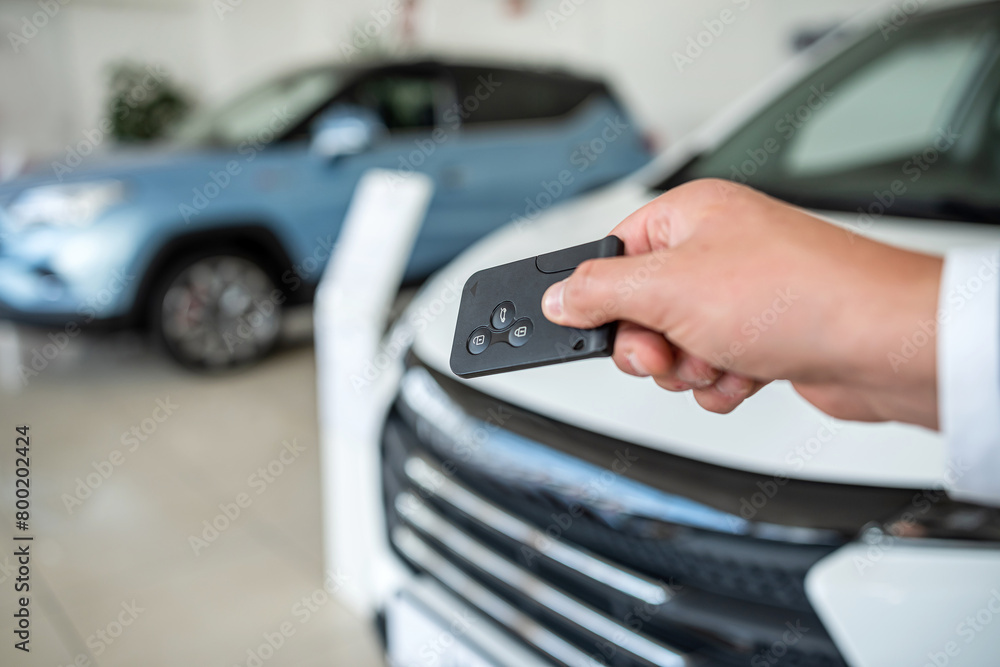 Fototapeta premium dealer hand holding key against new auto at showroom. success deal