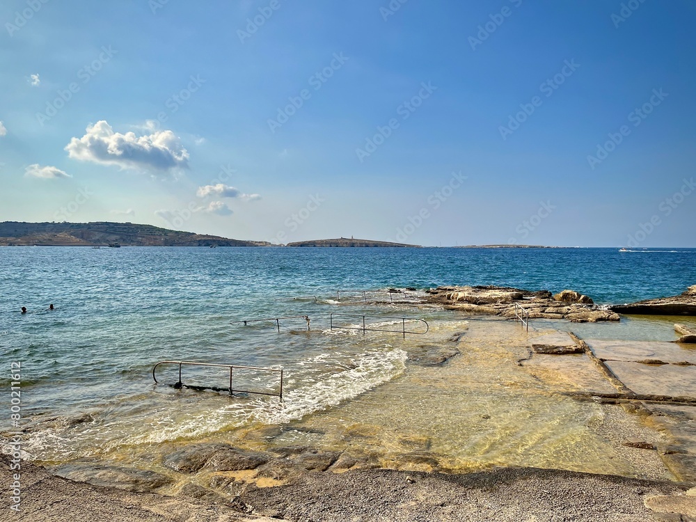 seascape of Malta from a rocky coast of St Paul's Bay on a summer day with a view of a typical Maltese rocky beach
