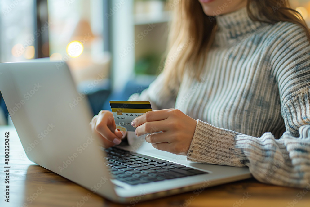 A woman is inputting her credit card information into her laptop A woman is inputting her credit card information into her laptop