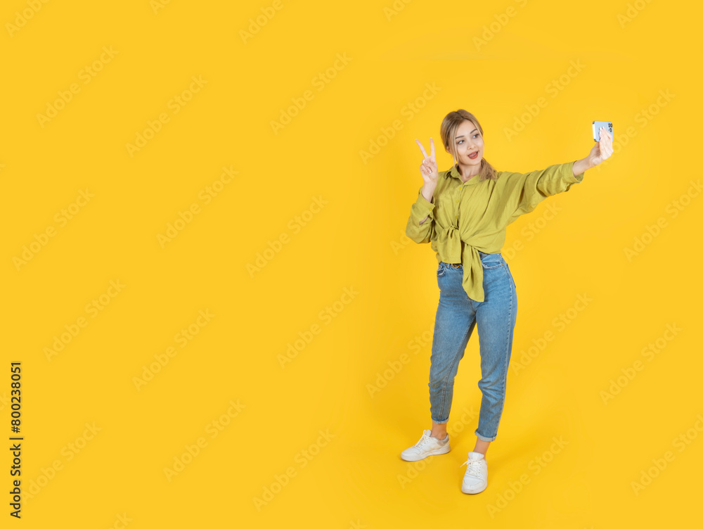Full body portrait of beautiful charming blonde girl 20s woman taking make selfie show v-sign isolated yellow background copy space. Advertising banner design concept photo idea. People lifestyle. Full body portrait of beautiful charming blonde girl 20s woman taking make selfie show v-sign isolated yellow background copy space. Advertising banner design concept photo idea. People lifestyle.