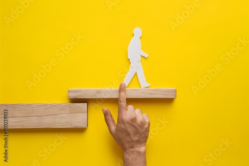 Vibrant yellow background with hand pointing at silhouette on wooden plank, symbolizing movement and progress photo