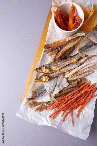 Various fish snacks and dried fruits on wooden table