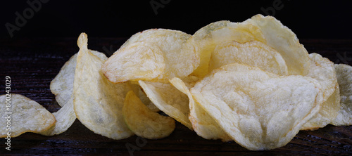 Potato chips on a dark background. Chips on a wooden board