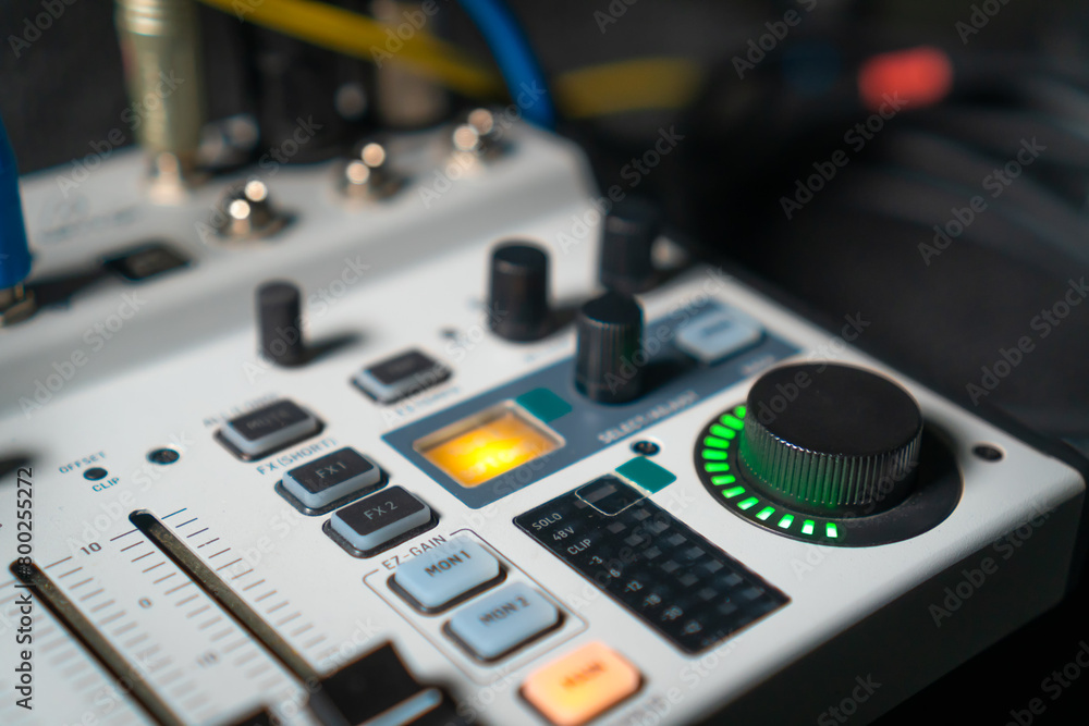 Close-up image of hand adjusting mixer knob for volume control during live studio performance. Mixer features multiple knobs and buttons for precise audio mix adjustments. Close-up image of hand adjusting mixer knob for volume control during live studio performance. Mixer features multiple knobs and buttons for precise audio mix adjustments.