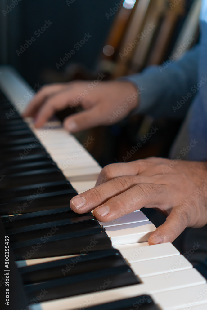 Fototapeta premium Close-up of male hands playing an electronic piano. Musical education at a music school. Private music lessons with a teacher. Vertical photo