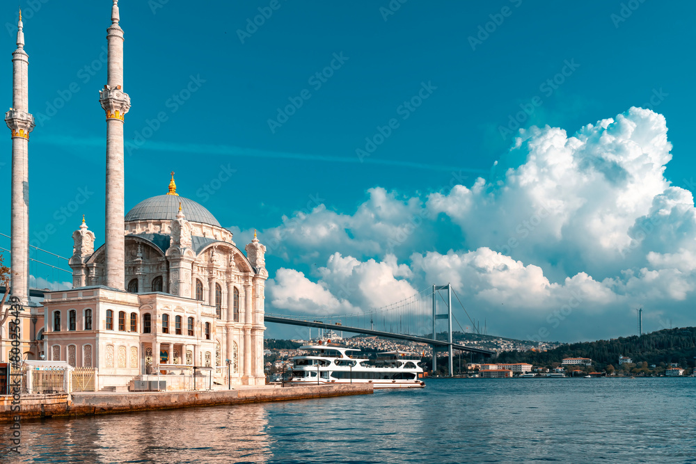 A mosque with a blue sky in the background. Ortakoy Mosque, Besiktas Turkey. A mosque in Istanbul with the bridge in the background.