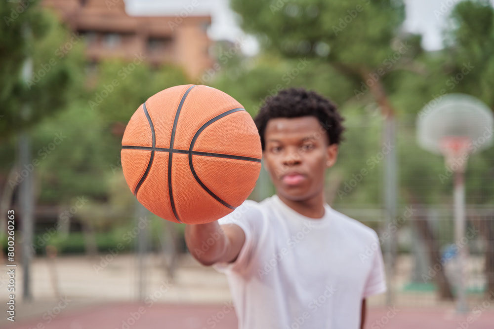 portrait of a young black man on a basketball court with a ball portrait of a young black man on a basketball court with a ball