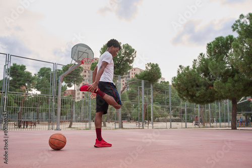 young African-American basketball player stretching his legs before playing © Oscar