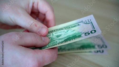 A man counts out money for monthly utility bills. Male hands counting fifty dollar bills close up. photo